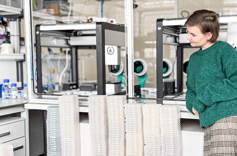 Paulina Wach, Head of Chemistry, standing next to 384-well plate stacks